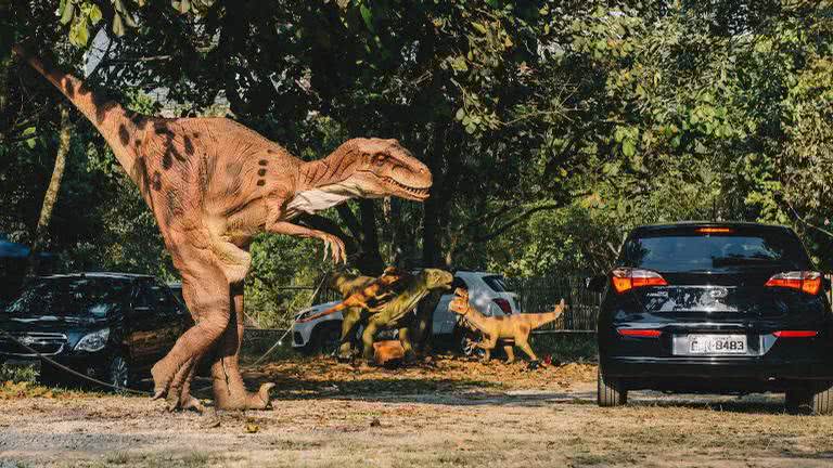 Foto dos dinossauros robóticos caminhando entre os carros - Divulgação
