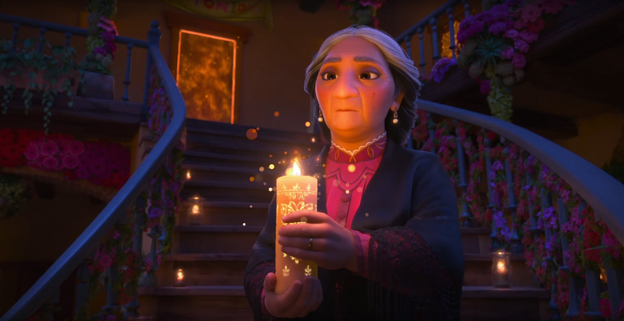 Personagem Abuela Alma segura uma vela enquando desce às escadas
